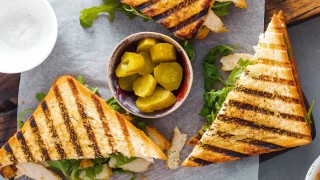 toasted chicken sandwich on a wooden board with pickles