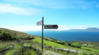 Sheeps head walking trail signpost with the Beara Peninsula across Bantry bay in the distance