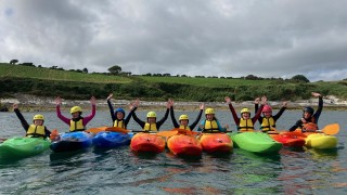 A group of kayakers in a row with their hands in the air