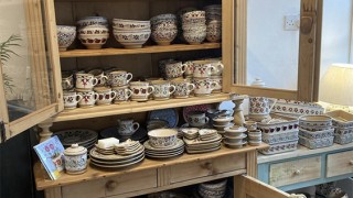 An old-fashioned wooden cabinet filled with lots of different kinds of pottery