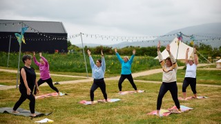 women participate in an outdoor yoga class with beara mountains in the background