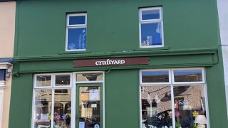 The exterior of CraftYard, a small shop painted green with white windows