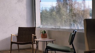 An interior shot of the Little Island Resort - two vintage lounge chairs stand in front of a large window overlooking the pool and patio